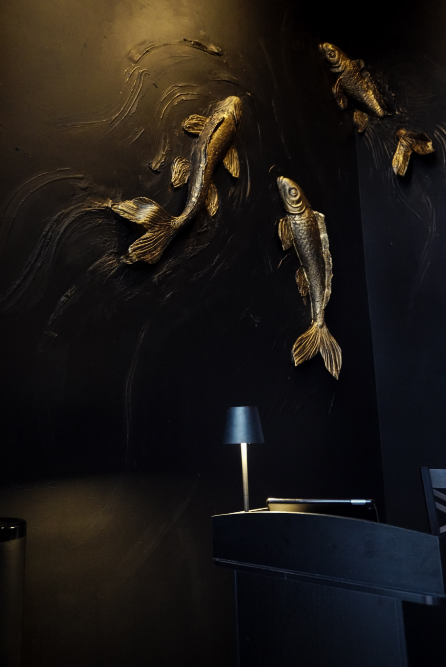The intimate Tokyo Club Sushi Speakeasy dining room in warm, moody light.